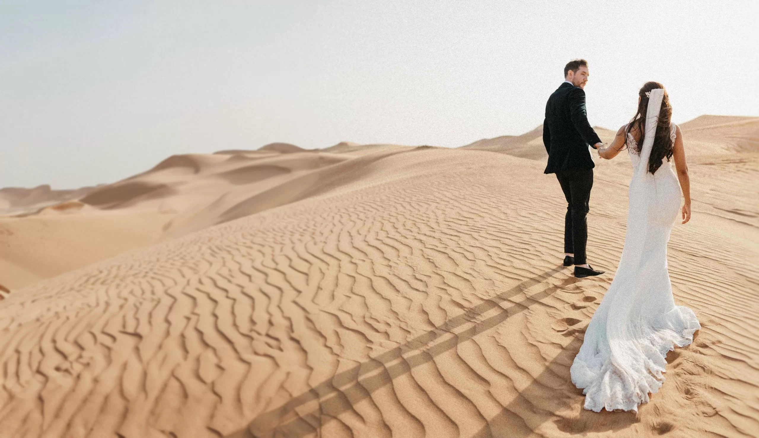 Wedding couple walking on desert dunes